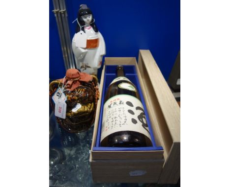 SAKE: THREE BOTTLES to include a large bottle in wood-effect case and two ceramic decanters (3)