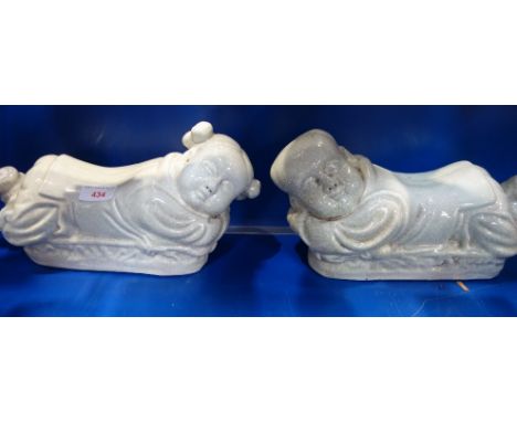A CHINESE WHITE CRACKLE GLAZED CERAMIC PILLOW in the form of a sleeping child, 33cm long and another similar (2)