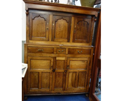 A GEORGE III OAK COURT CUPBOARD, above the straight cornice with two turned finials, below three cupboard doors, single shelf