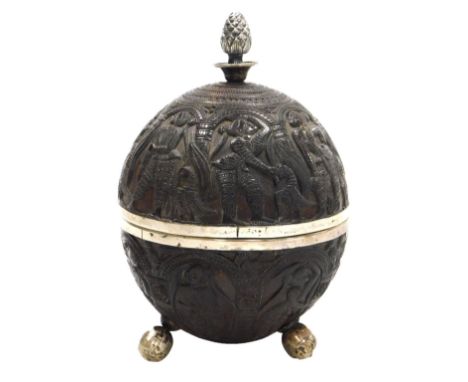 A 19thC Indian coconut cup and cover, carved with panels of ladies within repeating arches, the cover with a white metal pine