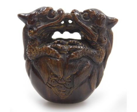 A contemporary Japanese style hardwood netsuke, carved as two dragons embraced over a bell signed, 4cm wide.