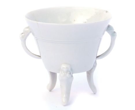 An 18thC Qing dynasty blanc-de-chine porcelain libation cup, of twin handed, tapering form, raised on three mask capped, scro