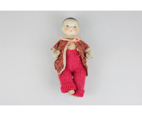 A German bisque porcelain head oriental doll with brown glass eyes, composite body and limbs, 22cm