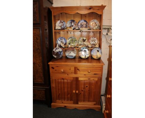 A pine dresser, two shelves above two drawer base, with two panelled doors enclosing a single shelf cupboard with round handl