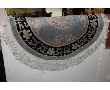 A Chinese circular rug with central floral motif on grey ground with black border, 92cm diameter