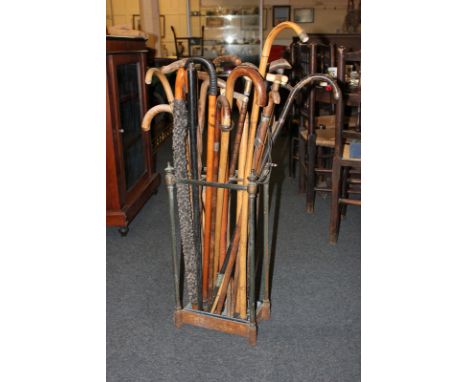 A cast iron stick stand with approximately twenty walking sticks, some with bone and horn handles (a/f - wormed) (NC)