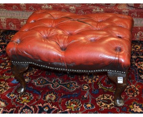 A red leather button top footstool, with studded edges raised on cabriole legs, 30cm high x 60cm wide x 45cm deep