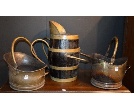 A vintage brass and wooden bound log bucket, 51cm high, together with two brass coal helmets (3)