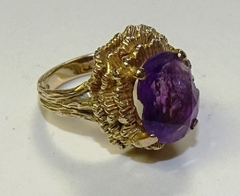 A 9ct gold amethyst ring, the large oval cut amethyst set in foliate layered gold mount (stone chipped), stamped 375 to under