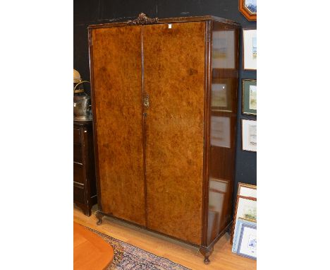 A vintage walnut wardrobe, with two panelled doors raised on small cabriole supports, 199cm high x 123cm wide x 54cm deep