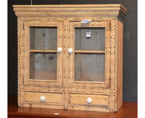 A vintage pine wall mounting cabinet, with two glazed doors, enclosing shelved interior, above two small drawers, 57cm high x