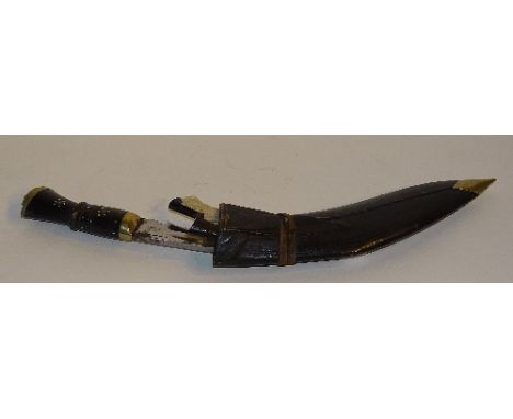 An Eastern Kukri knife, in leather scabbard, the ebonised handle with metal inlaid decoration and brass lion head mount, with