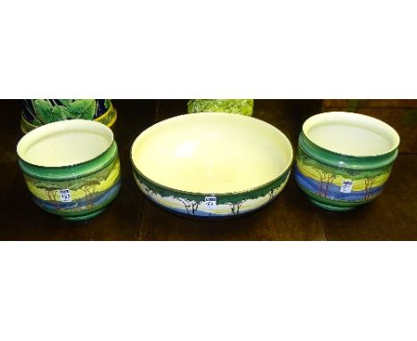 A pair of Art Deco Royal Doulton pottery jardiniere's, decorated with colourful central banding of trees in landscape on gree