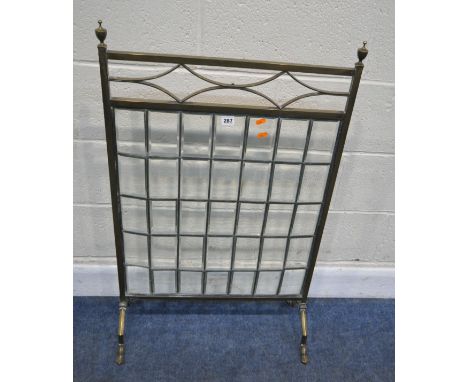 A BRASS FRAMED FIRE SCREEN, with twin finials, geometric top section, over thirty-five lead glazed bevelled glass panes, rais