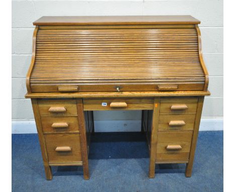 THE LEBUS DESK, AN EARLY 20TH CENTURY OAK DESK, the tambour top enclosing a fitted interior, over seven assorted drawers, wid