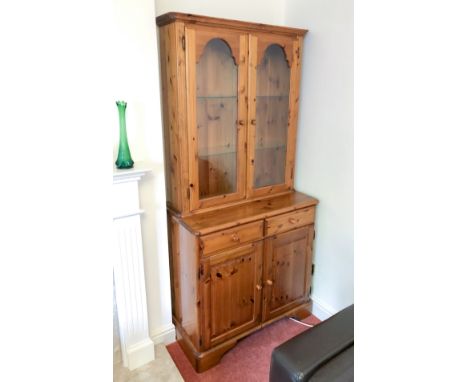 A Ducal pine glazed cupboard bookcase or dresser - the moulded top over a pair of arched glazed doors enclosing two adjustabl