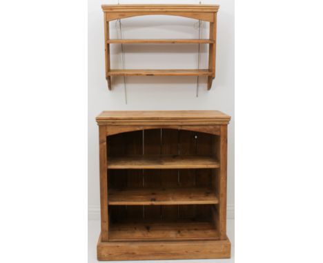 A waxed-pine open bookcase of small proportions - the moulded top over an arched apron and three open shelves, on a chamfered