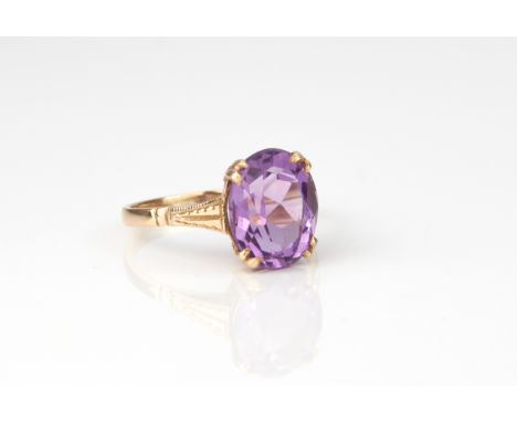 A 9ct yellow gold and amethyst ring - stamped '9CT', the 11 x 9mm. oval cut amethyst over bright cut shoulders, size M.