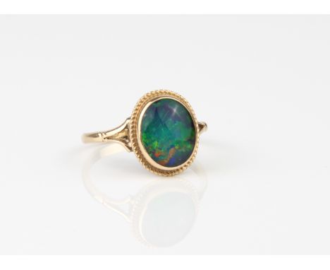 A 9ct yellow gold and black opal triplet ring - hallmarked Birmingham 1979, the 10 x 8.5mm. opal triplet within a rope twist 