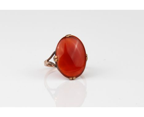 An antique 9ct rose gold and carnelian ring - stamped '9CT', early 20th century, the 18.5 x 12.5 mm oval cabochon carnelian o