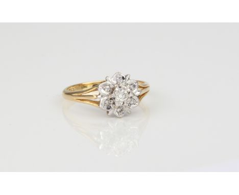 An 18ct yellow gold and diamond daisy cluster ring - stamped '18CT', with a bright cut, floral style cluster with seven brill