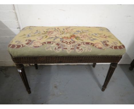 An early 20th century Louis XVI inspired mahogany finished stool with a tapestry top and acanthus carved frieze on turned, ta