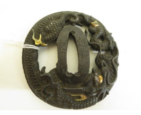 A Japanese 18th century Tsuba decorated with dragons and gold highlights, the rim decorated with dragon scales, signed, 2 3/4