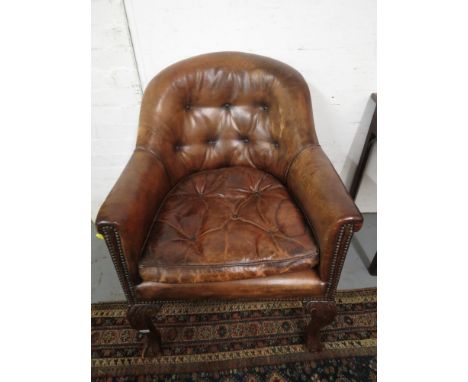 An early 20th century brown button upholstered armchair with an arched back and cushion seat, raised on mahogany cabriole leg