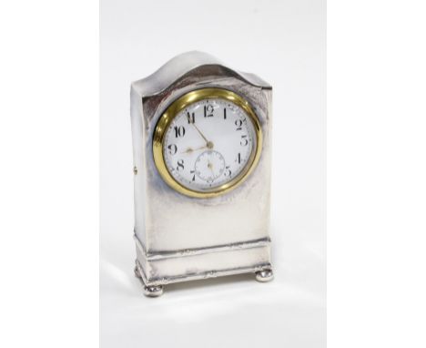 An Edwardian silver dressing table clock, Chester 1910, simple case with an arched top, standing on bun feet, white enamel di