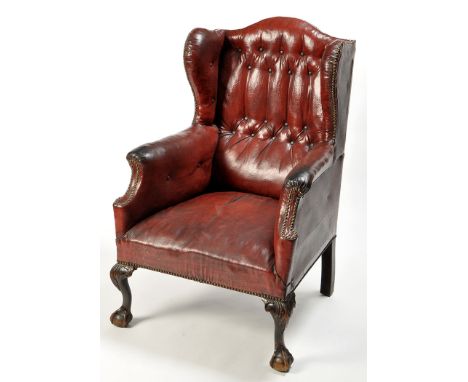 A late 19th Century Georgian style wing back armchair, the brass studded red leather cloth buttoned back, arms and seat, rais