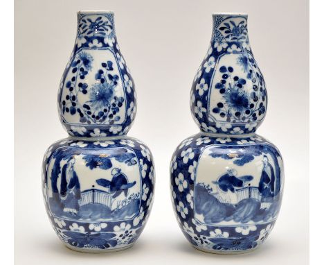 Pair of Chinese blue and white double gourd shaped vases, each with panels having flower blooms above garden landscapes with 