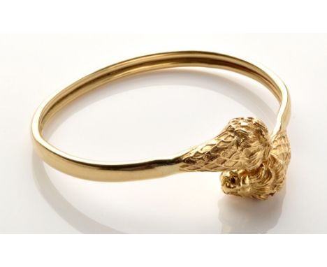 A yellow metal bangle, the terminals decorated with lion masks on a double tubular bangle, stamped four times "18ct.", 7.7cms