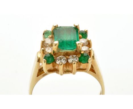 An emerald and diamond cluster ring, the central rectangular facet cut emerald corner set surrounded by eight brilliant cut d