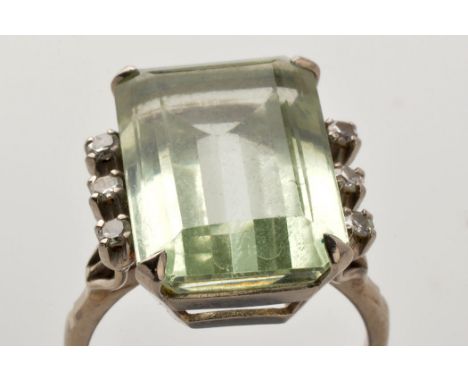 A light green coloured gemstone and diamond ring, the emerald-cut gemstone probably aquamarine, flanked by three eight-cut di