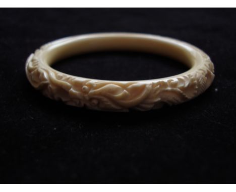 An early 20th Century Chinese ivory bangle, carved with two scrolling dragons. 