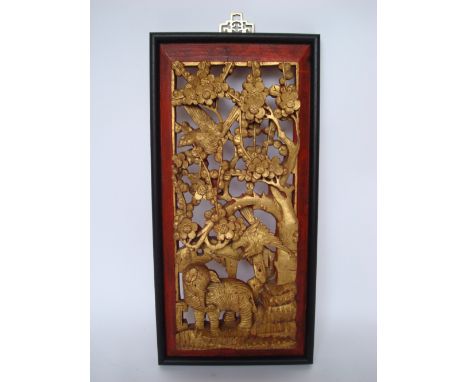 An early 20th Century Chinese giltwood and painted wall panel, deeply carved and pierced with an elephant and birds in the br