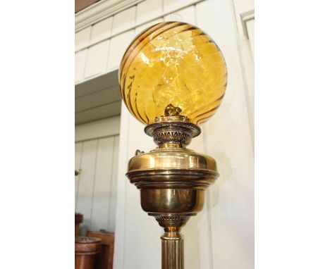 Victorian brass oil lamp with an orange spiral glass shade, 78cm high.