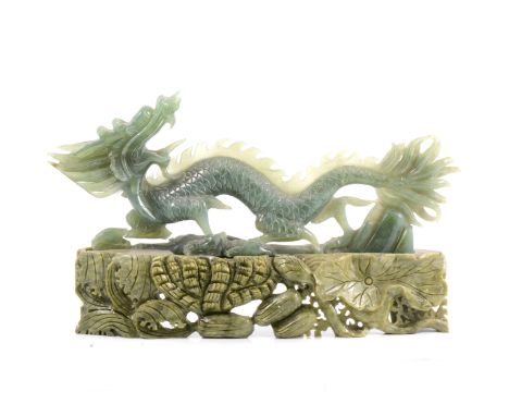 Carved nephrite jade dragon sculpture on a carved soapstone base, 38cm wide, some damages.