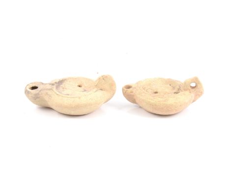 A Roman terracotta oil lamp, imperial eagle to centre, hole in handle, circa 1st to 4th century AD, 10.5cm; and another with 