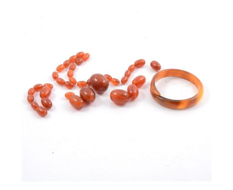 An amber coloured bead necklace, egg shaped graduated beads, 64cm,an amber coloured 13mm D shape crossover bangle.