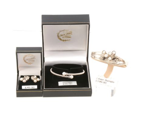 Two new silver bangles set with cultured pearls, an open ended bangle in a modern fluid design set five pearls in a stylistic