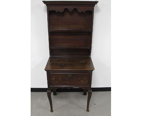 An antique oak dresser, of small proportions, top with enclosed panel back, two shelves with moulded corners and shaped pedim