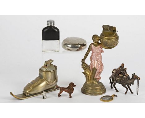 Three novelty lighters, modelled as a ski boot, a camel rider and a woman carrying a basket, together with a small silver cat