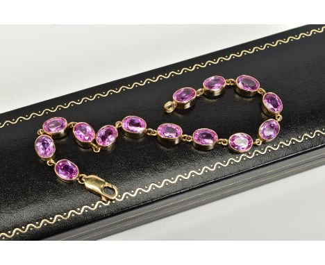 A 9CT GOLD LINE BRACELET, set with fourteen oval mix cut pink sapphires, each within a collet mount, fitted to a lobster claw