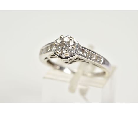 A DIAMOND CLUSTER RING, the raised white metal ring with a central circular cluster set with round brilliant cut diamonds, wi