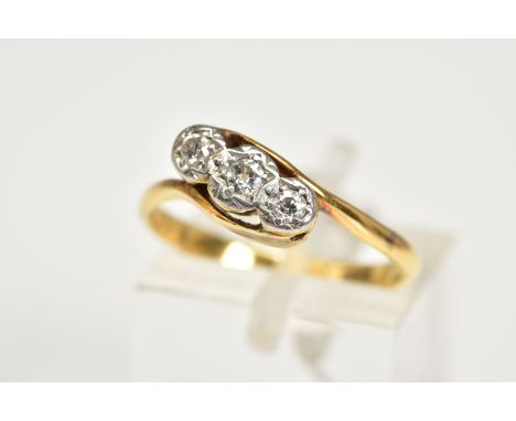 A YELLOW METAL THREE STONE DIAMOND RING, of cross over design with a central old cut diamond flanked by round brilliant cut d