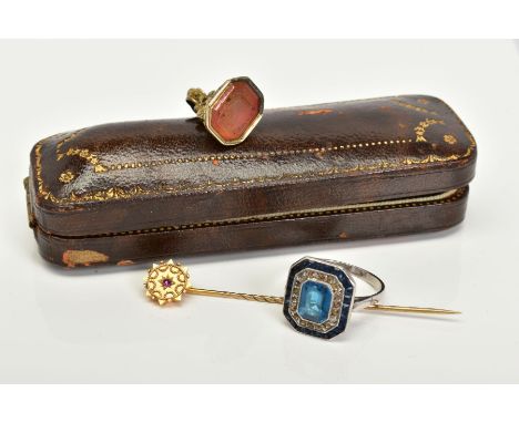 A STICK PIN AND FOB, the Victorian stick pin set with a circular cut ruby, within a yellow metal embossed surround, stamped 1