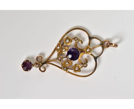AN EDWARDIAN YELLOW METAL BROOCH, of openwork design, central panel set with a purple garnet topped doublet, split pearl flor
