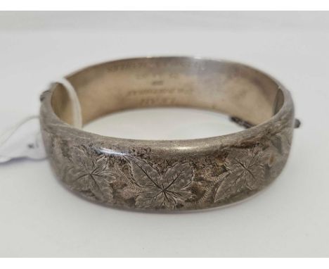 AN ENGRAVED HINGED SILVER BANGLE WITH SAFETY CHAIN