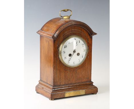 An Edwardian oak cased mantel clock with French eight day movement striking on a gong, the circular enamelled dial with black